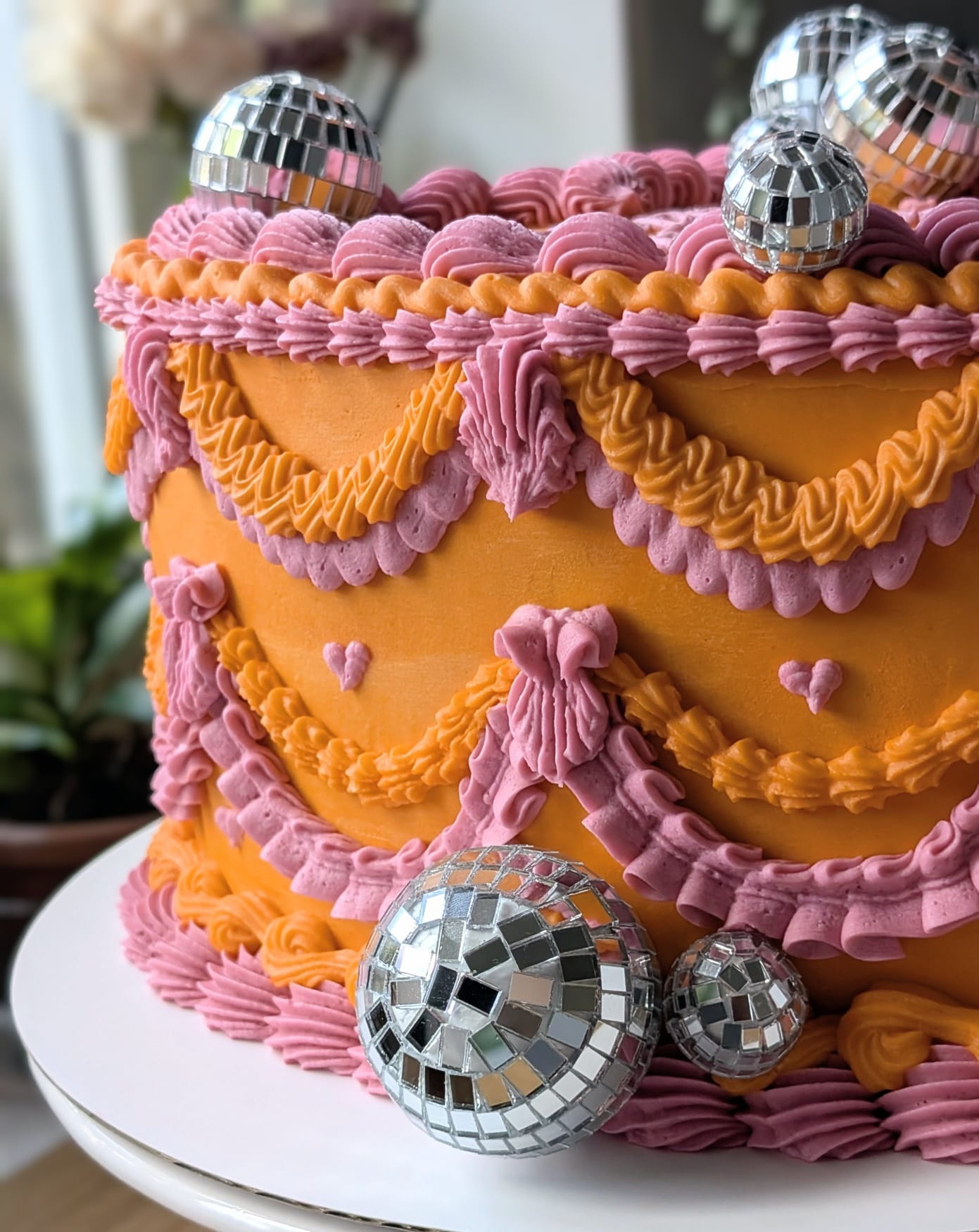 Orange and pink vintage-piped cake with disco balls