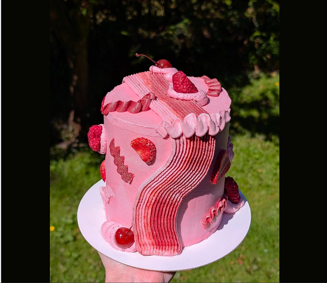 Pink hand-decorated celebration cake with cherries and berries