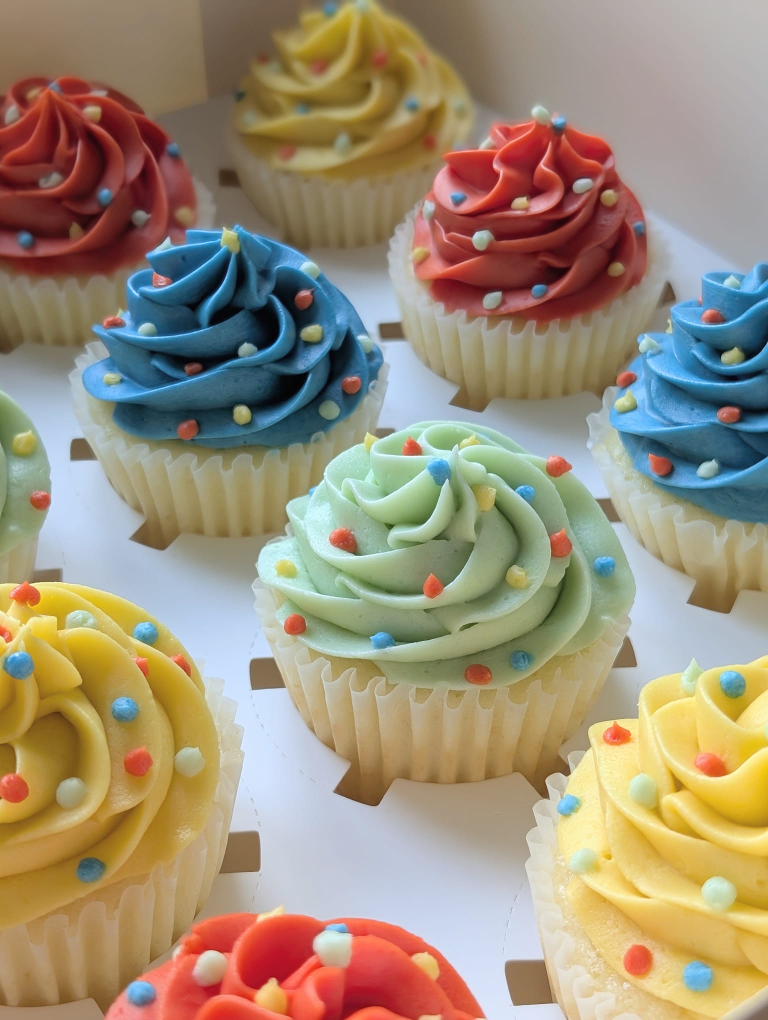 Box of colourful hand-piped cupcakes