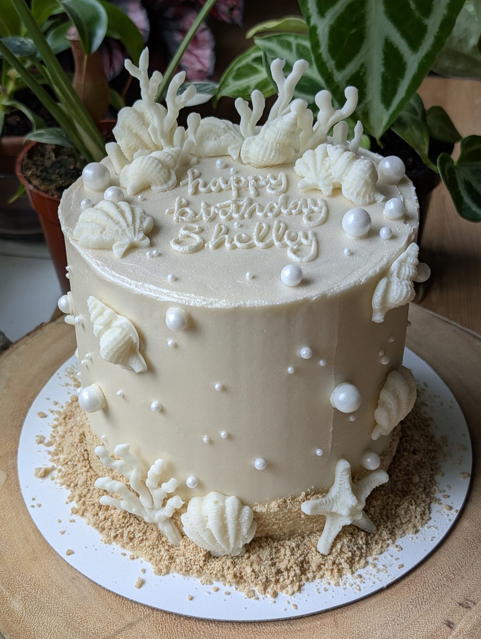 White seashell cake with piped happy birthday lettering